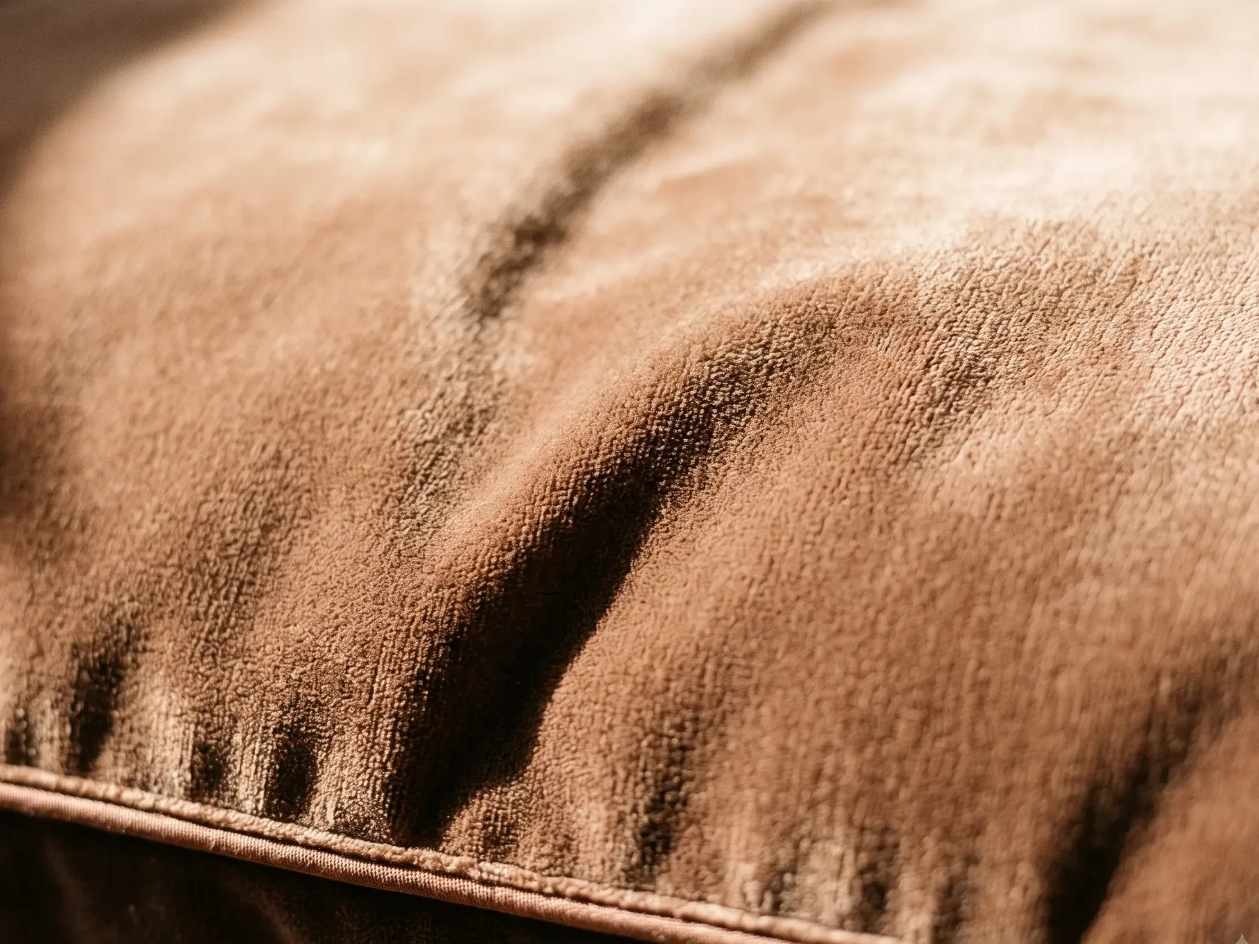 Close detail of velvet upholstery, the nap of the pile crossed by light